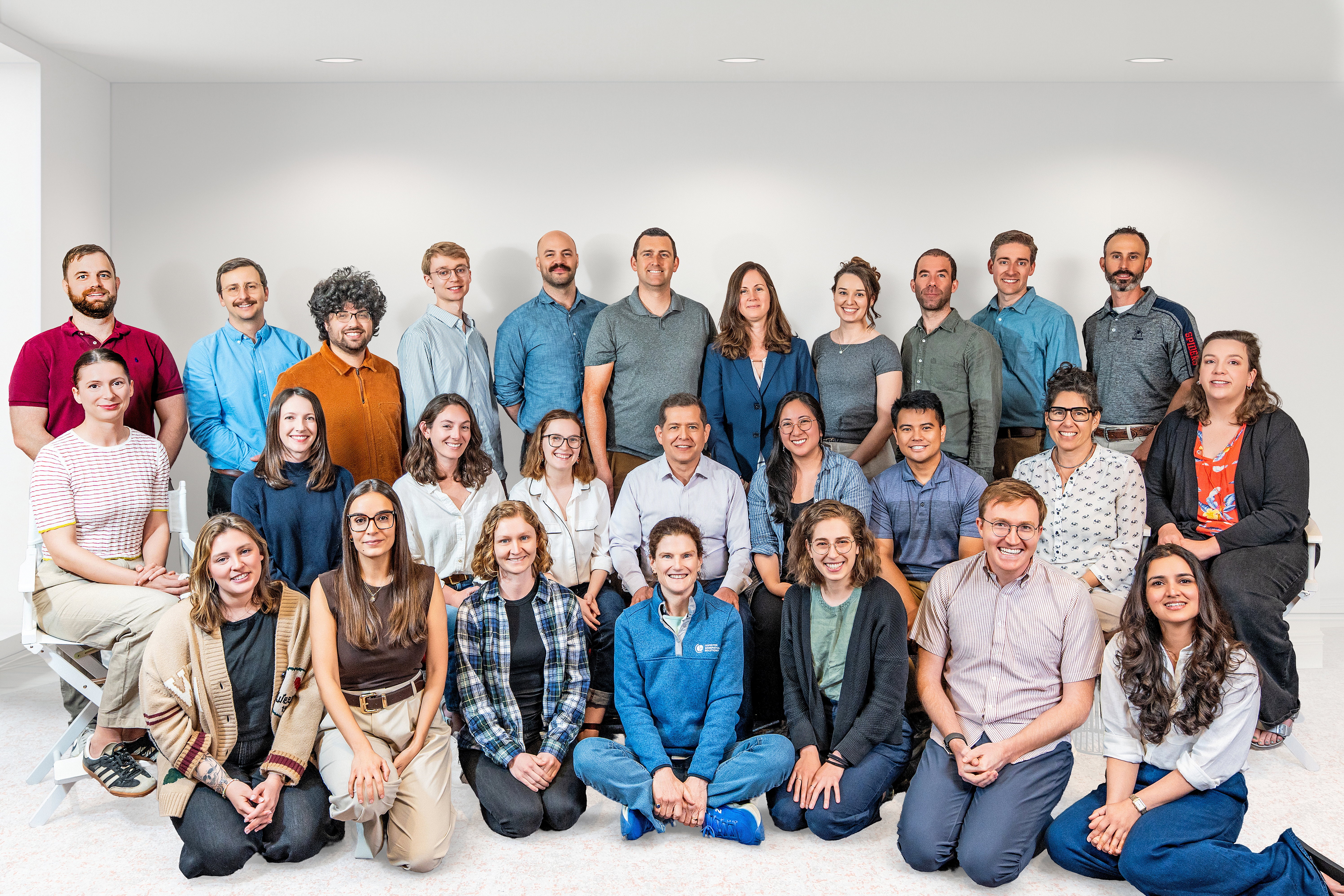 The CGS team posed together in 3 rows in a white room.