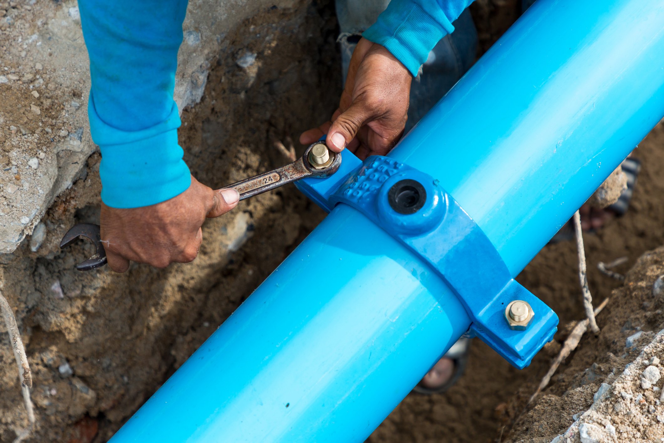 Hands repairing a blue water pipe. 